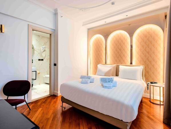Une chambre d’hôtel moderne, dotée d’un grand lit, d’un bureau et d’une chaise.