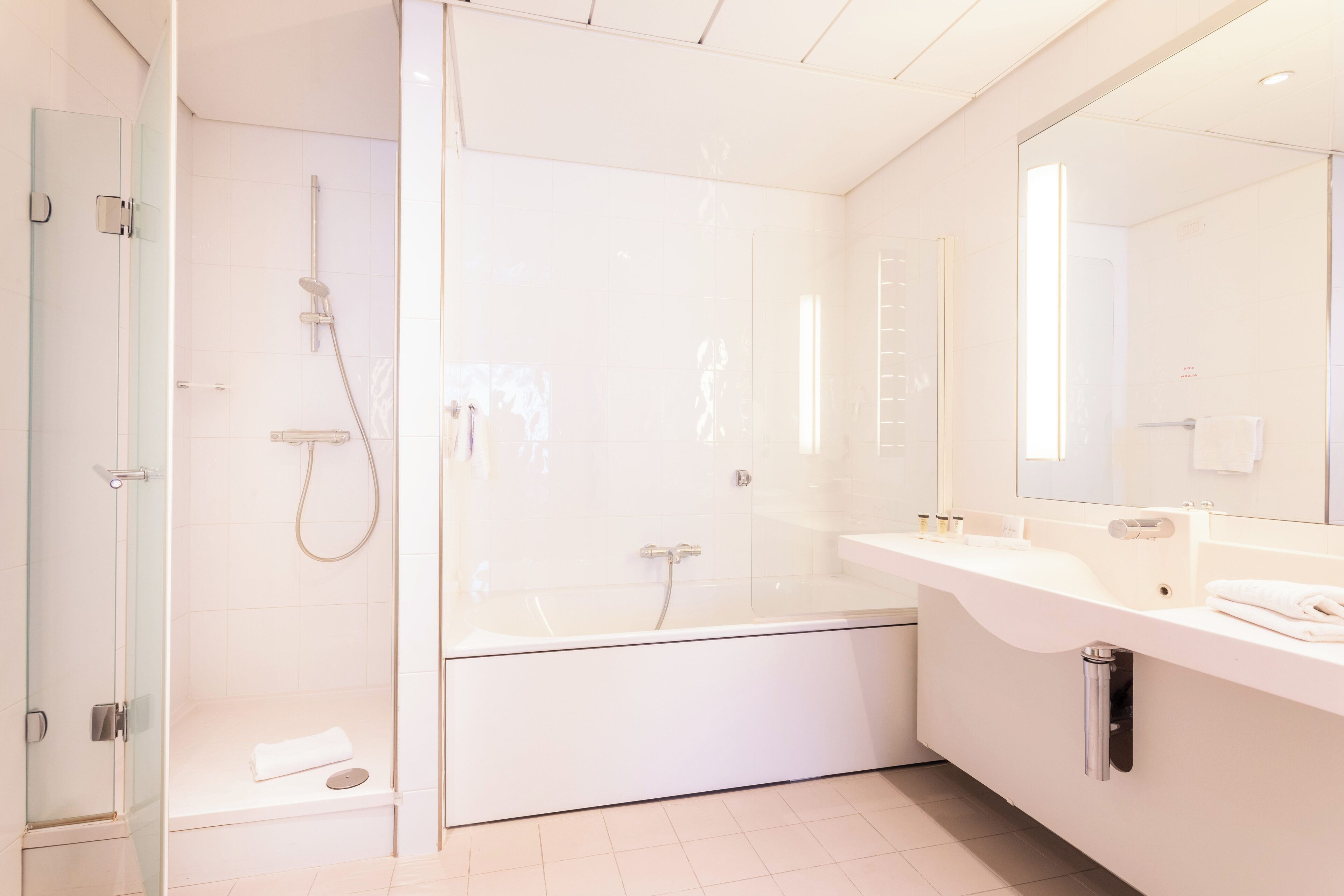 Een moderne badkamer met een douchecabine van glas, een vrijstaand bad en een wastafel met spiegel en aanrecht.
