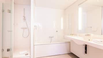 Un baño moderno con ducha de vidrio, bañera independiente y tocador con espejo y encimera.