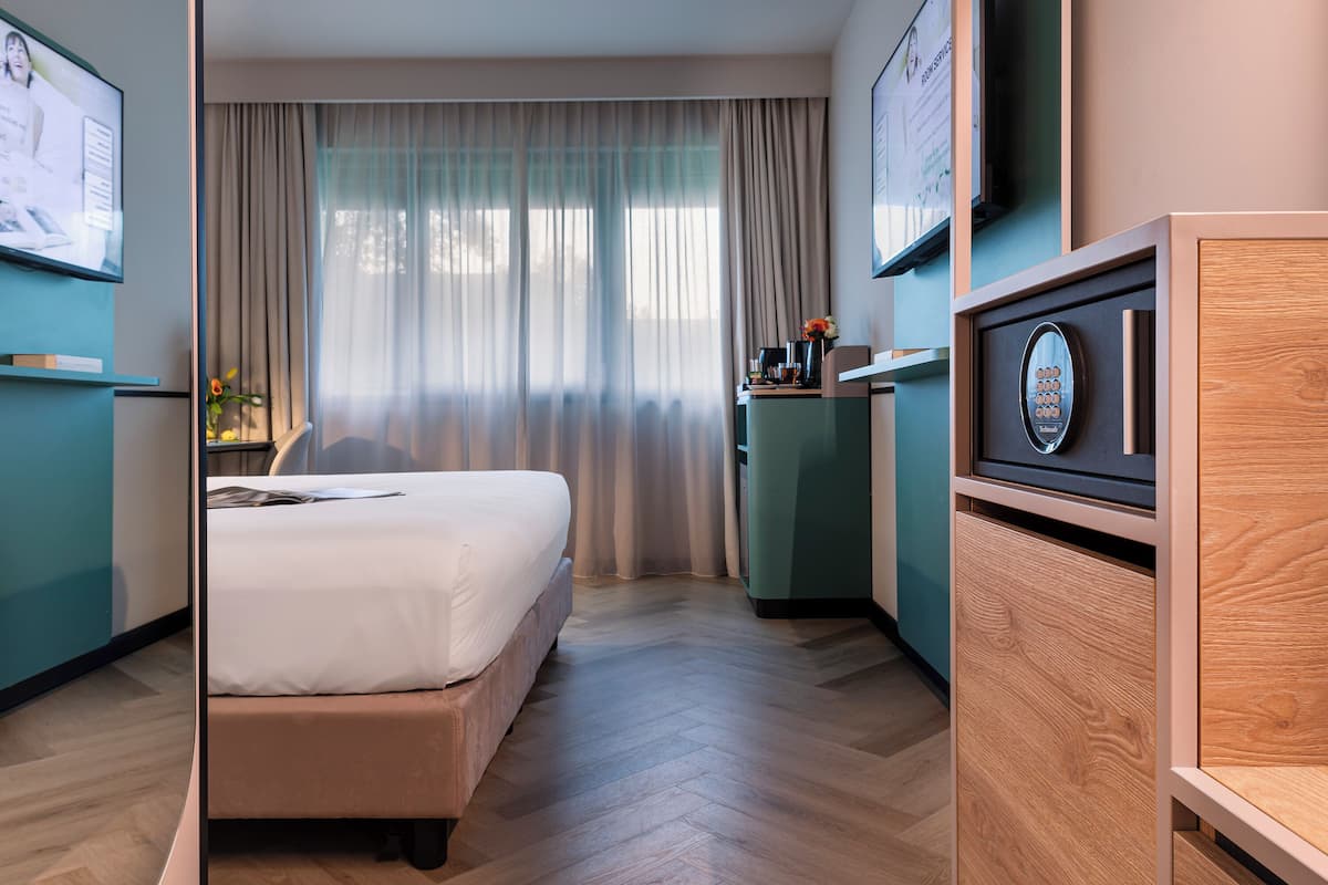Ein Hotelzimmer mit einem Bett, einem Schreibtisch, einem Fernseher und einem Holzkabinett.