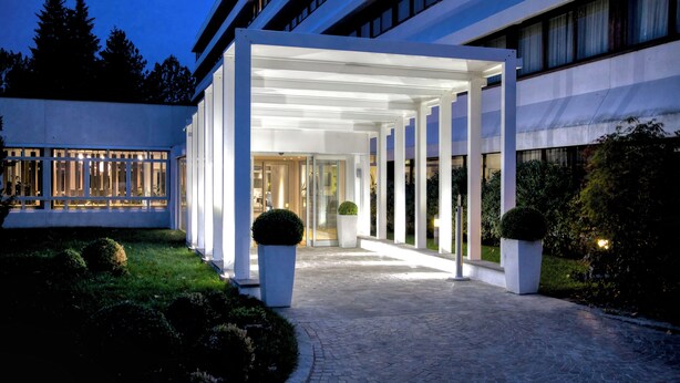 A modern building with a covered entrance, large windows, and a paved pathway. - Living Place Hotel (Bologna)