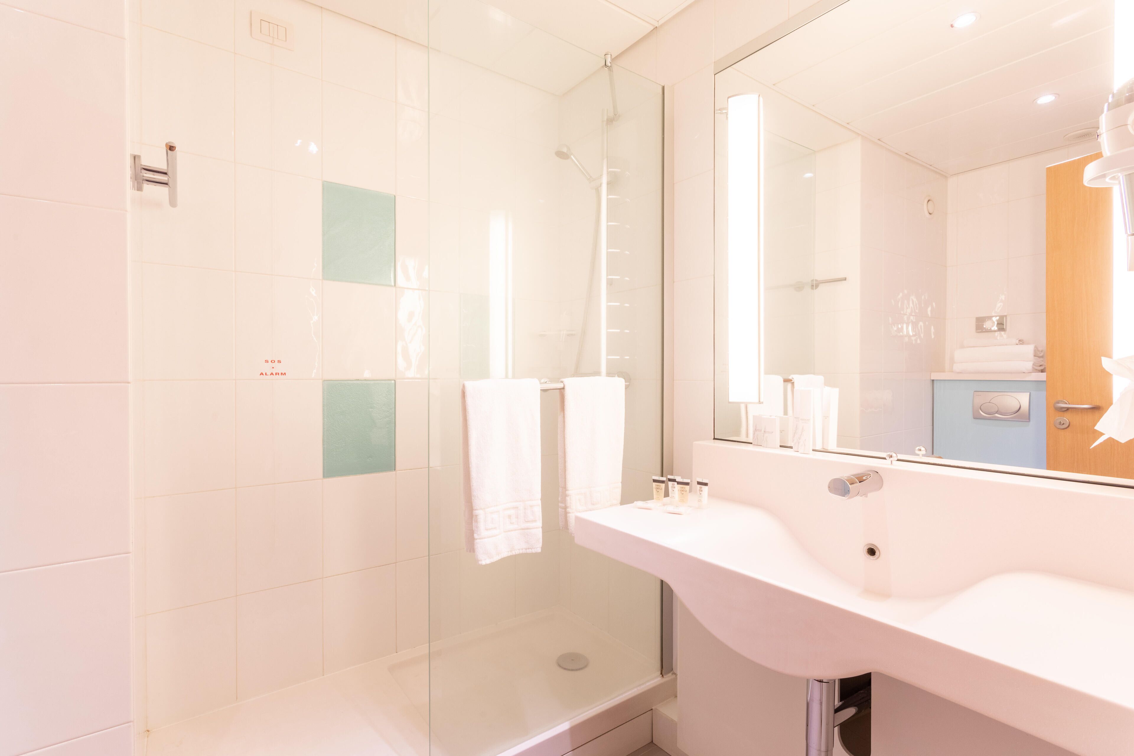 A modern bathroom with a glass-enclosed shower, a white sink, and a large mirror.