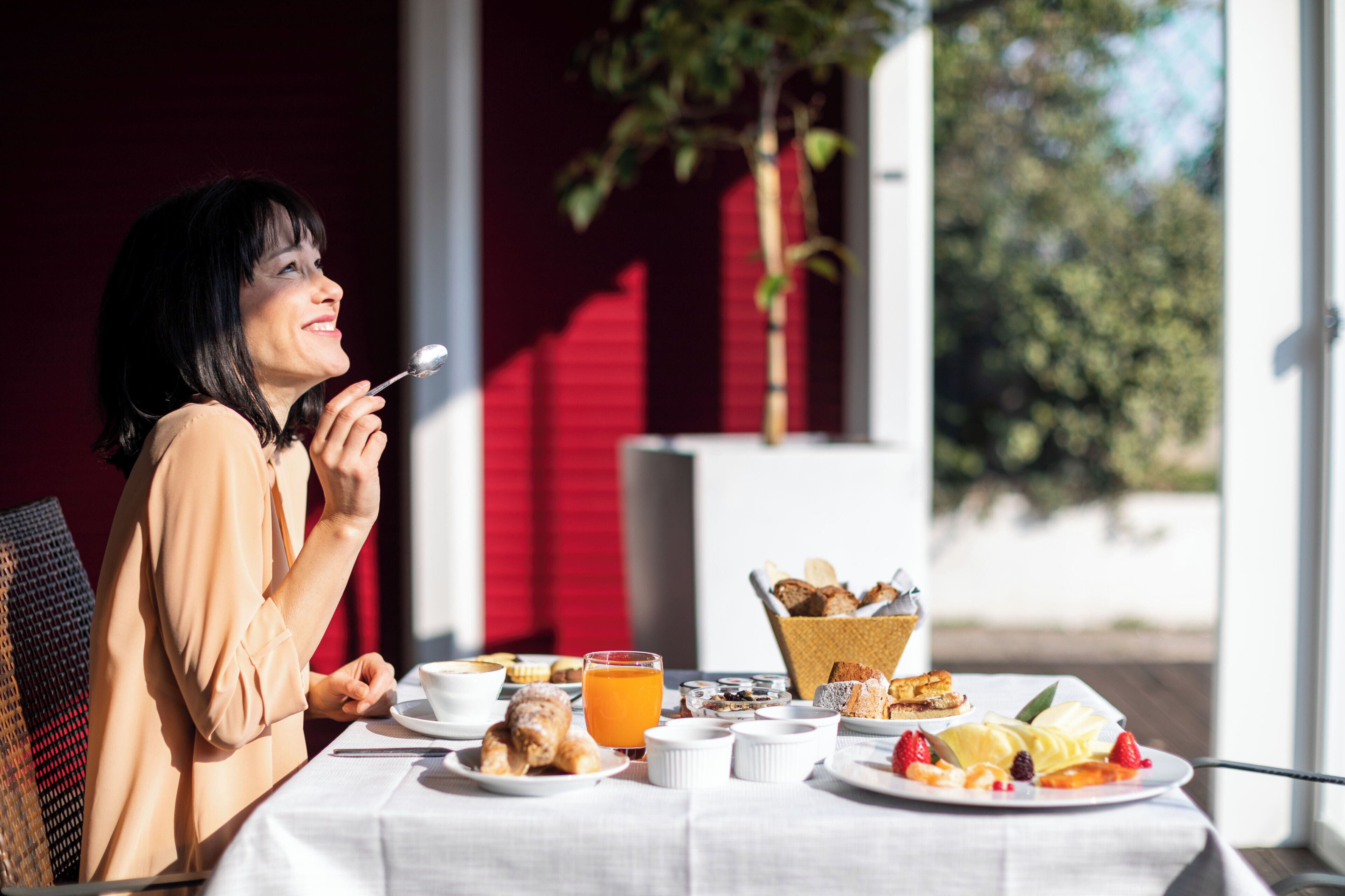 A dining table with various breakfast items including pastries, fruits, and a glass of orange juice.