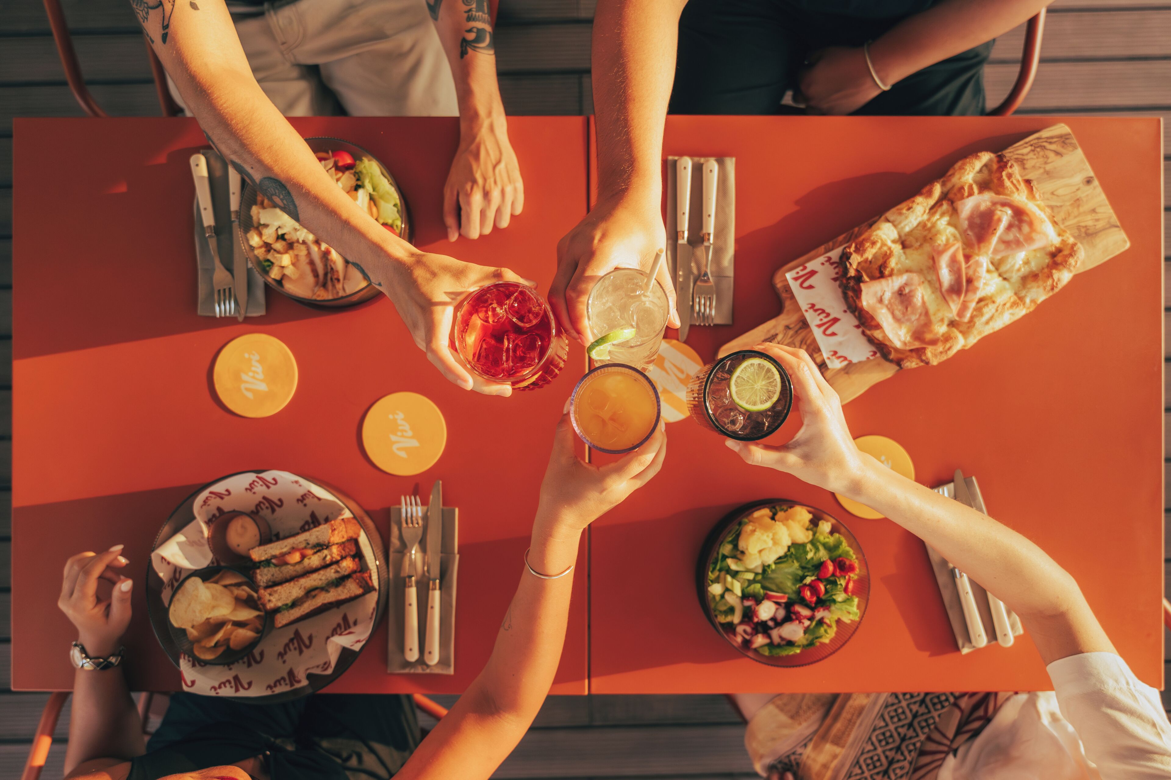 A group of people seated around a table with various dishes, drinks, and utensils.