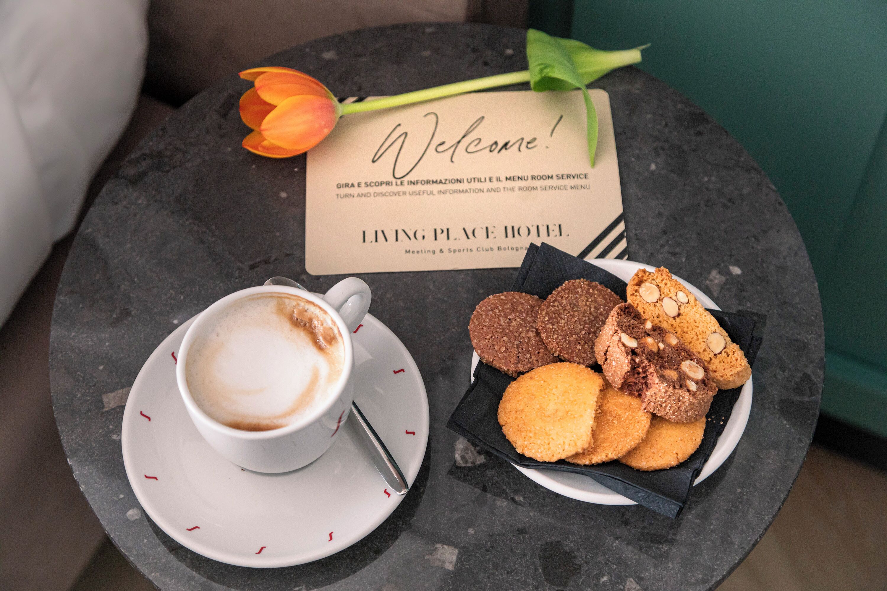 A coffee cup and a plate of cookies on a table with a welcome sign.
