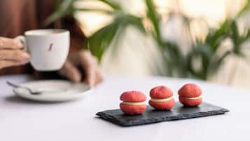 Una mesa con una bandeja de macarons y una taza de café.