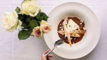 Une assiette blanche avec un dessert, une cuillère et un bouquet de roses blanches.
