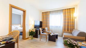 Relax in a stylish room with a sofa, armchairs, and a desk with TV and lamp.