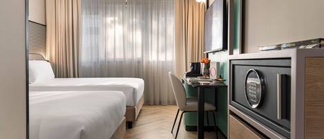 Una habitación de hotel con dos camas, un escritorio con computadora y un minibar.