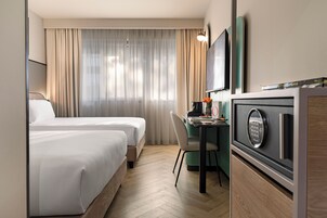 Una habitación de hotel con dos camas, un escritorio con computadora y un minibar.