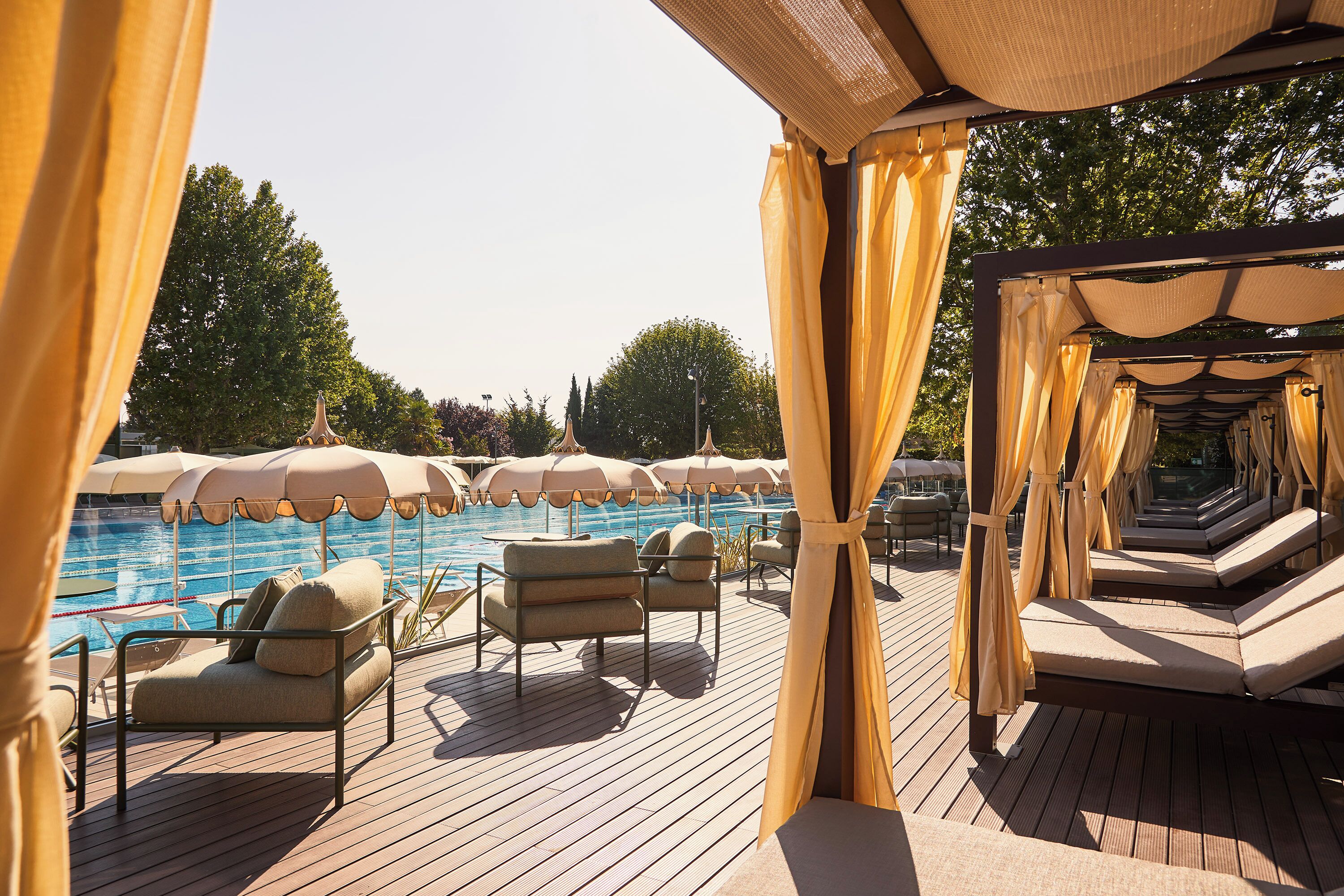 Un espace aménagé au bord de la piscine, avec des chaises longues et des parasols, une terrasse en bois et une vue sur la piscine.