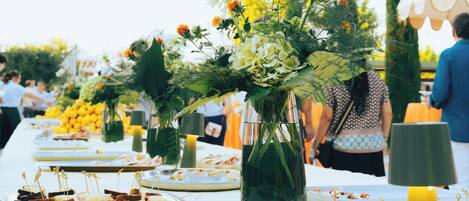 A buffet table with various food items and floral centerpieces.