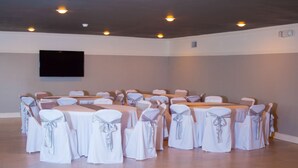 A conference room with multiple tables and chairs, a flat-screen TV mounted on the wall, and recessed ceiling lights. - Motel 6 Palestine, TX (Palestine)