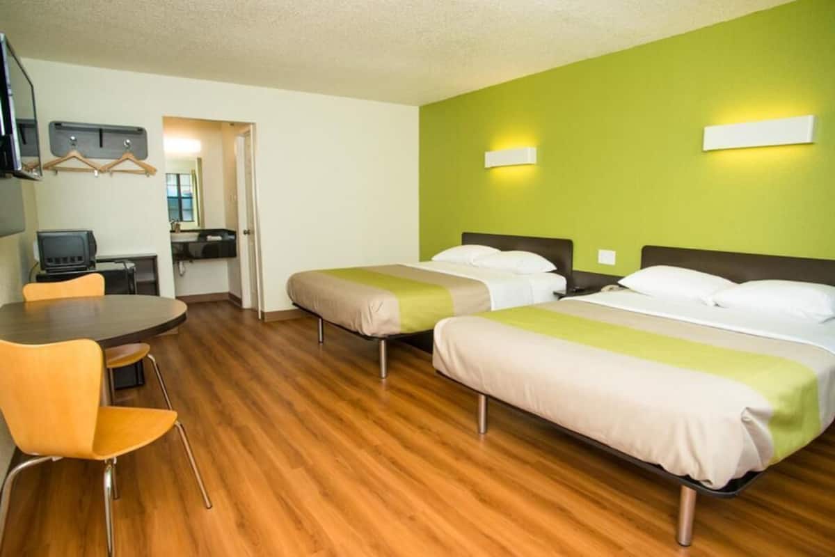 A hotel room with two beds, a desk, and a chair.