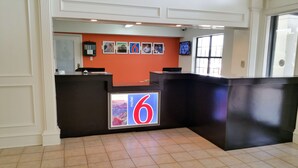 A reception area with a prominent '6' sign, a counter, and a wall with framed pictures. - Motel 6 Palestine, TX (Palestine)