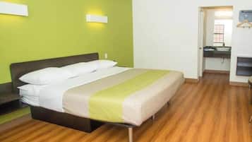 Habitación de hotel con cama, escritorio y baño visible a través de una puerta abierta.