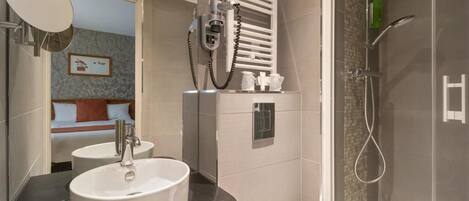 A modern bathroom with a large sink, a mirror, a hairdryer, and a shower.
