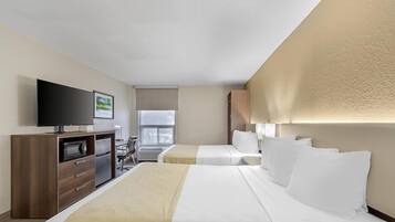 A hotel room with two beds, a TV, a desk with a chair, and a window.