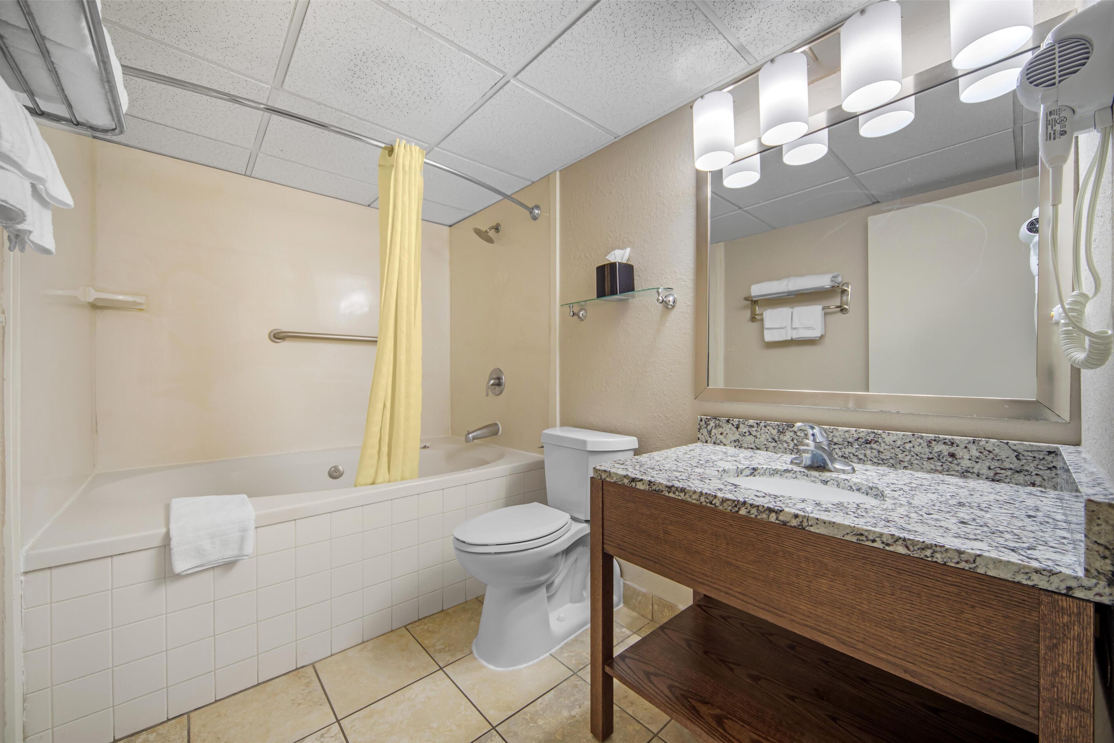 A modern bathroom with a bathtub, toilet, and vanity.