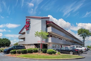 Un Red Roof Inn con un diseño moderno, varios balcones y un estacionamiento con varios coches.