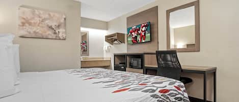 Een hotelkamer met een bed, een bureau, een stoel, een televisie en een spiegel.