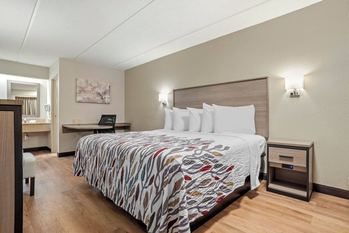 Een hotelkamer met een bed, nachtkastjes, een bureau en een badkamer.