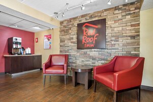 Vestíbulo de Red Roof Inn con pared de piedra, una máquina de café y sillones de cuero.