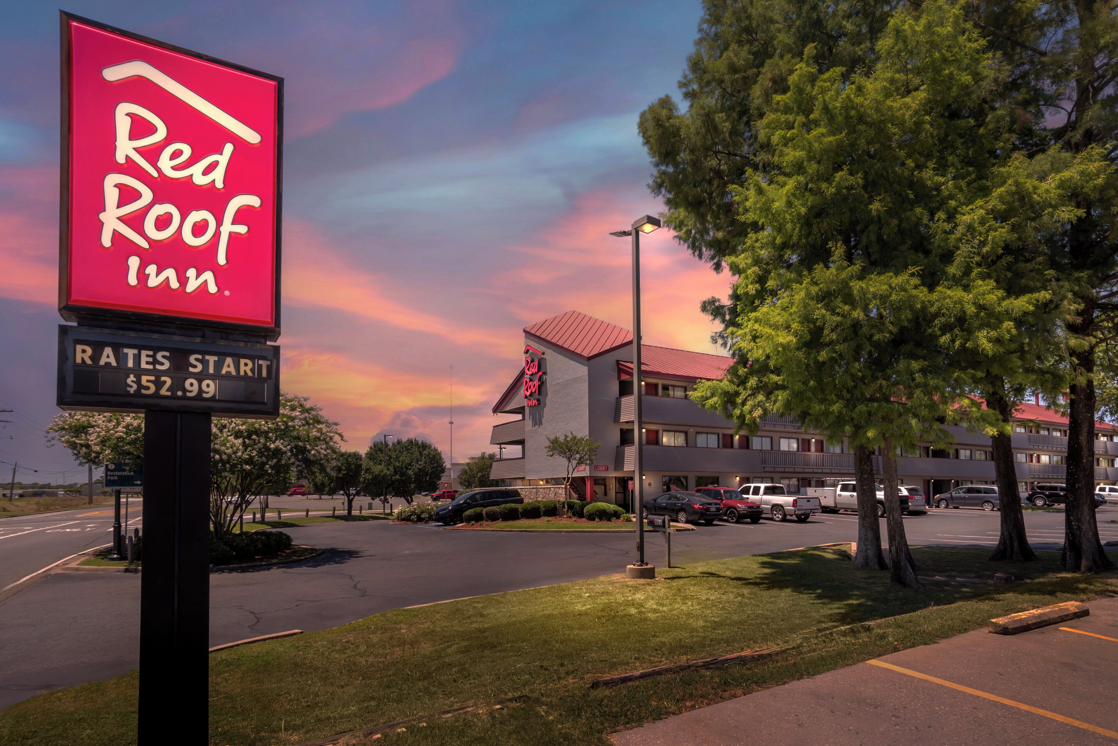 A Red Roof Inn sign with a clear sky and a building in the background.