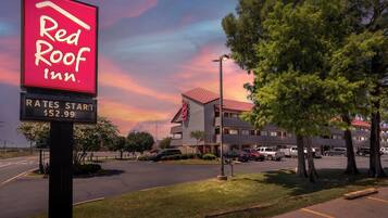 A Red Roof Inn sign with a clear sky and a building in the background.