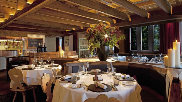 A restaurant with round tables, candles, and a large flower arrangement. - Mövenpick Hotel Zuerich-Airport (Opfikon)