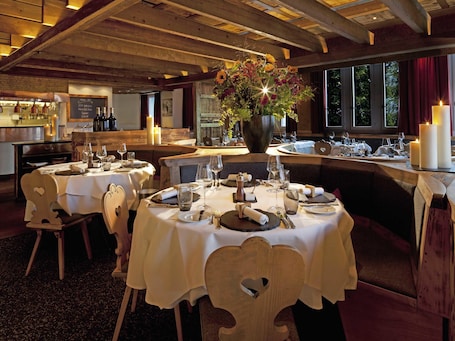 A restaurant with round tables, candles, and a large flower arrangement.