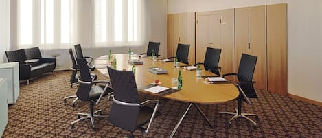 A conference room with a round table, chairs, and a projector screen.