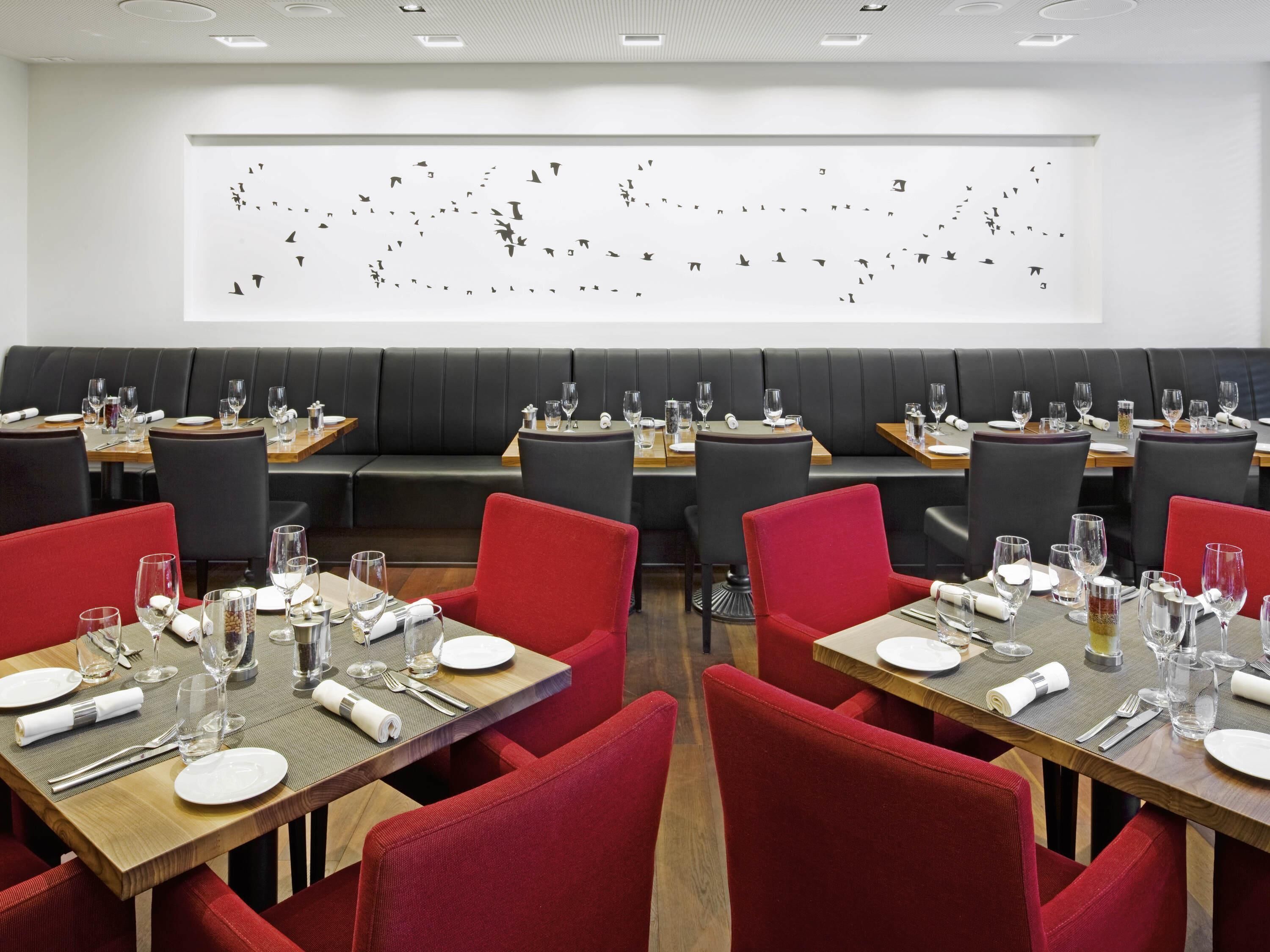 A restaurant with multiple tables and booths, each set with white plates, glasses, and cutlery.
