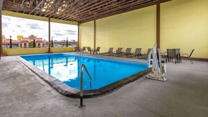 An indoor swimming pool with a view of a building in the background.