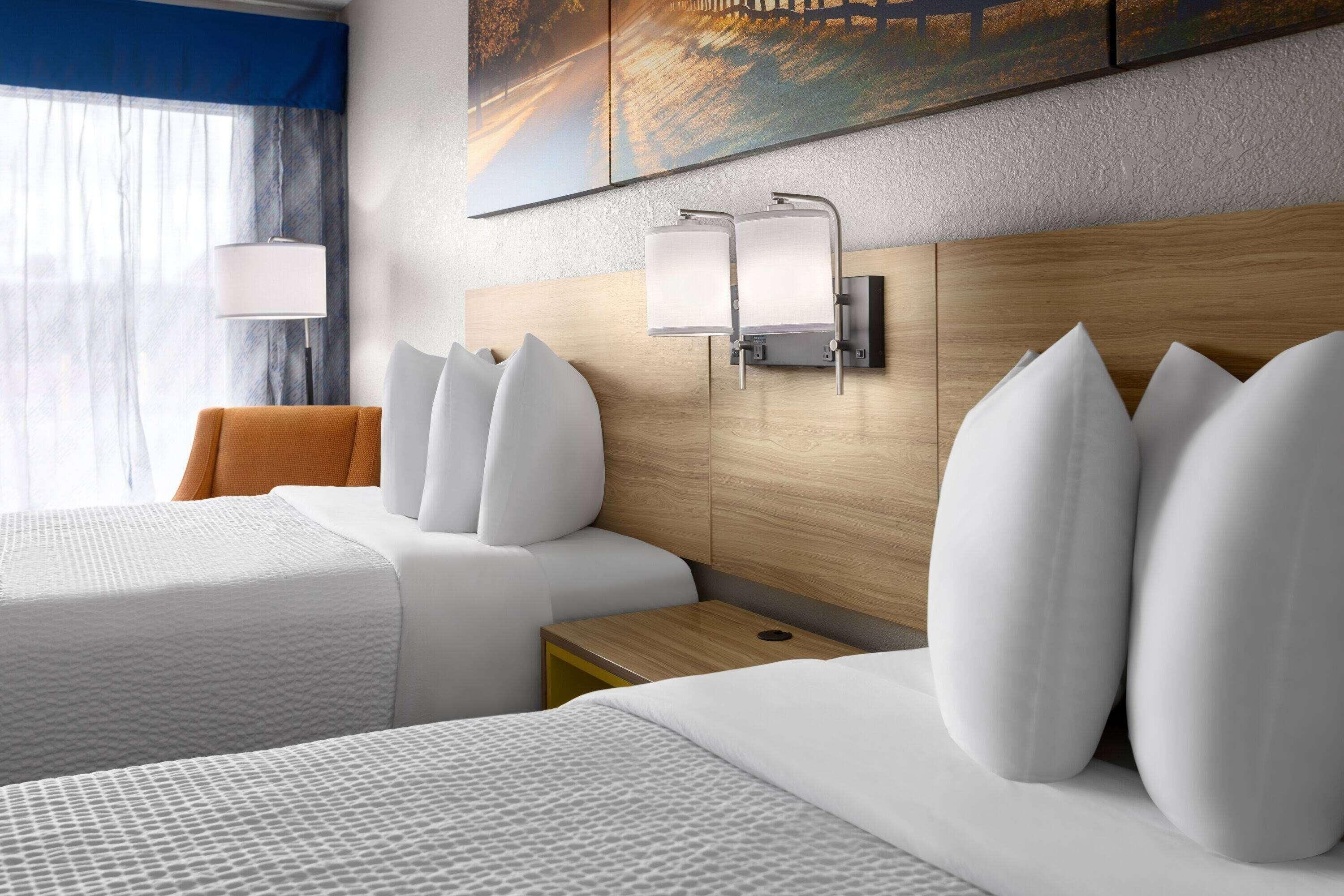 Ein Hotelzimmer mit zwei Betten, einem Nachttisch, einer Lampe und einem Bild an der Wand.