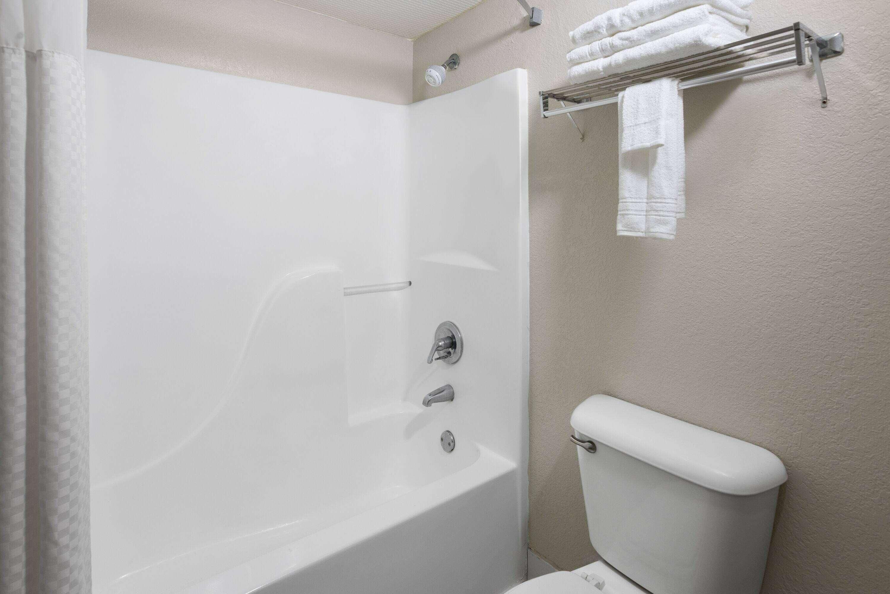 A bathroom with a bathtub, toilet, and towel rack.