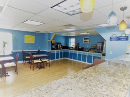 A restaurant with blue walls, wooden tables, and a marble counter.
