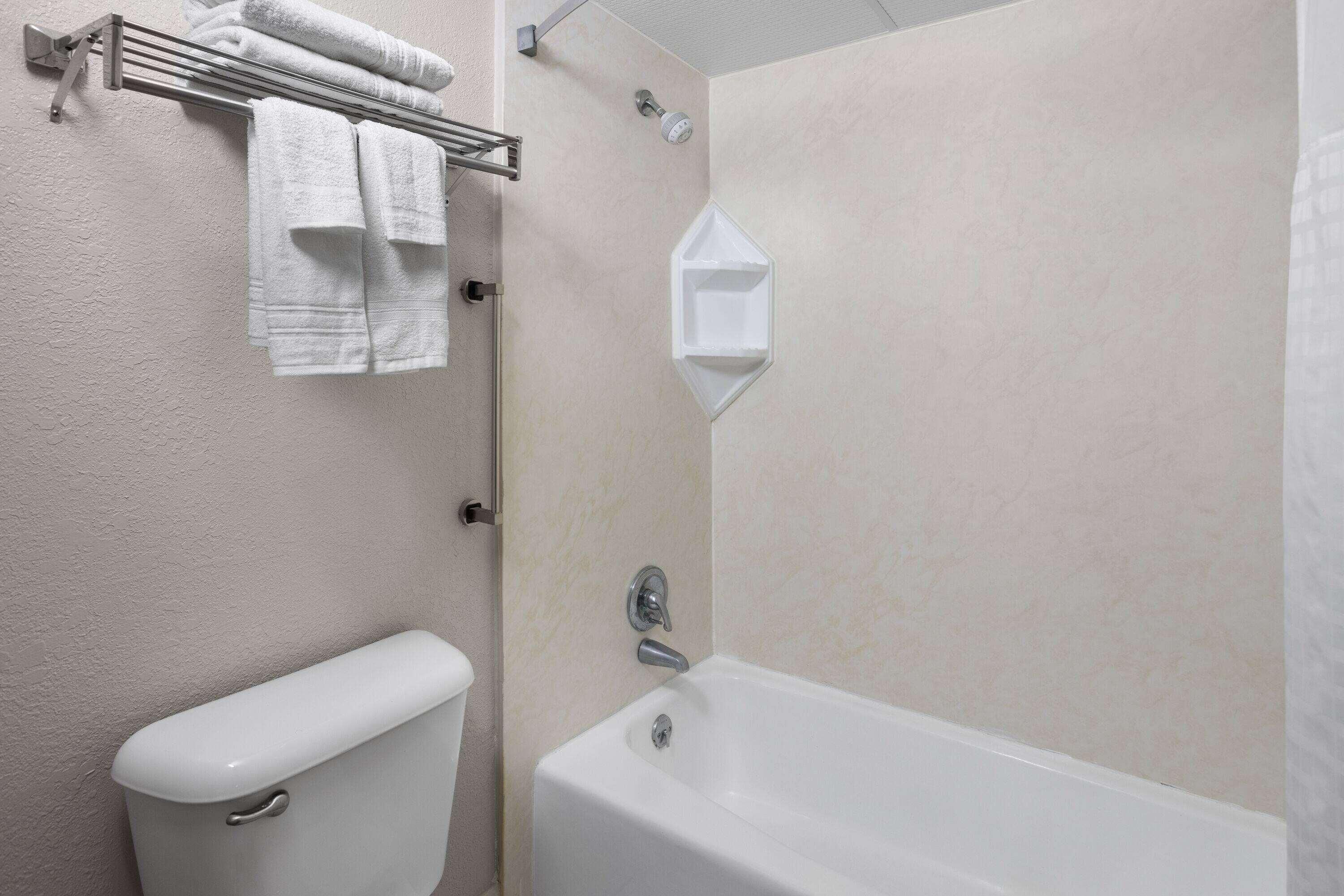 A bathroom with a toilet, a bathtub, and a towel rack with folded towels.