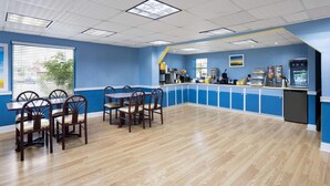 A restaurant with a blue and white color scheme, wooden flooring, and a counter with various appliances.