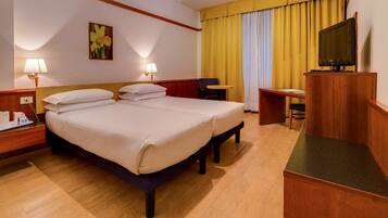 Ein Hotelzimmer mit Doppelbett, Schreibtisch, Stuhl, Fernseher und einem Bild an der Wand.