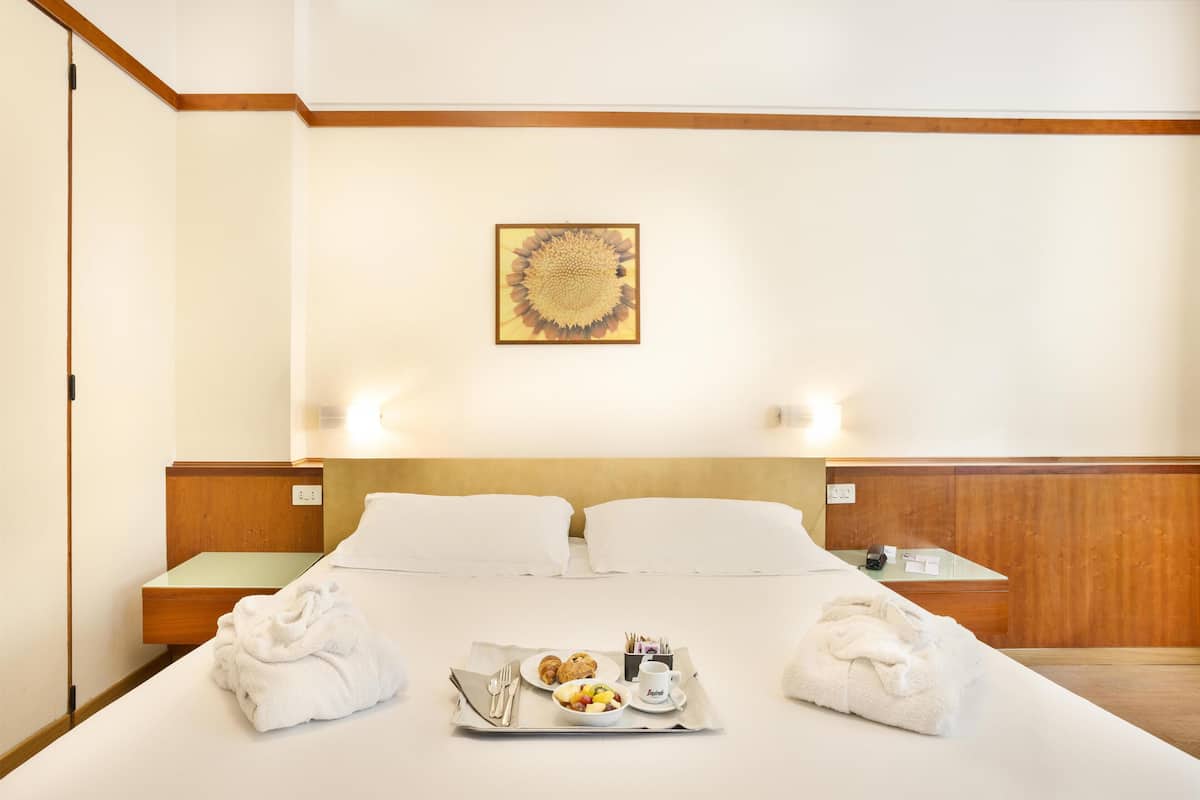 Une chambre d’hôtel avec un lit, un plateau contenant des articles pour le petit-déjeuner et un tableau accroché au mur.