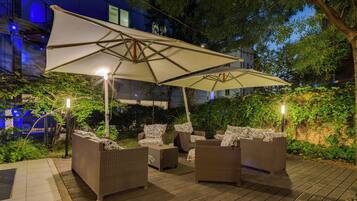 An outdoor seating area with wicker furniture and a large umbrella.