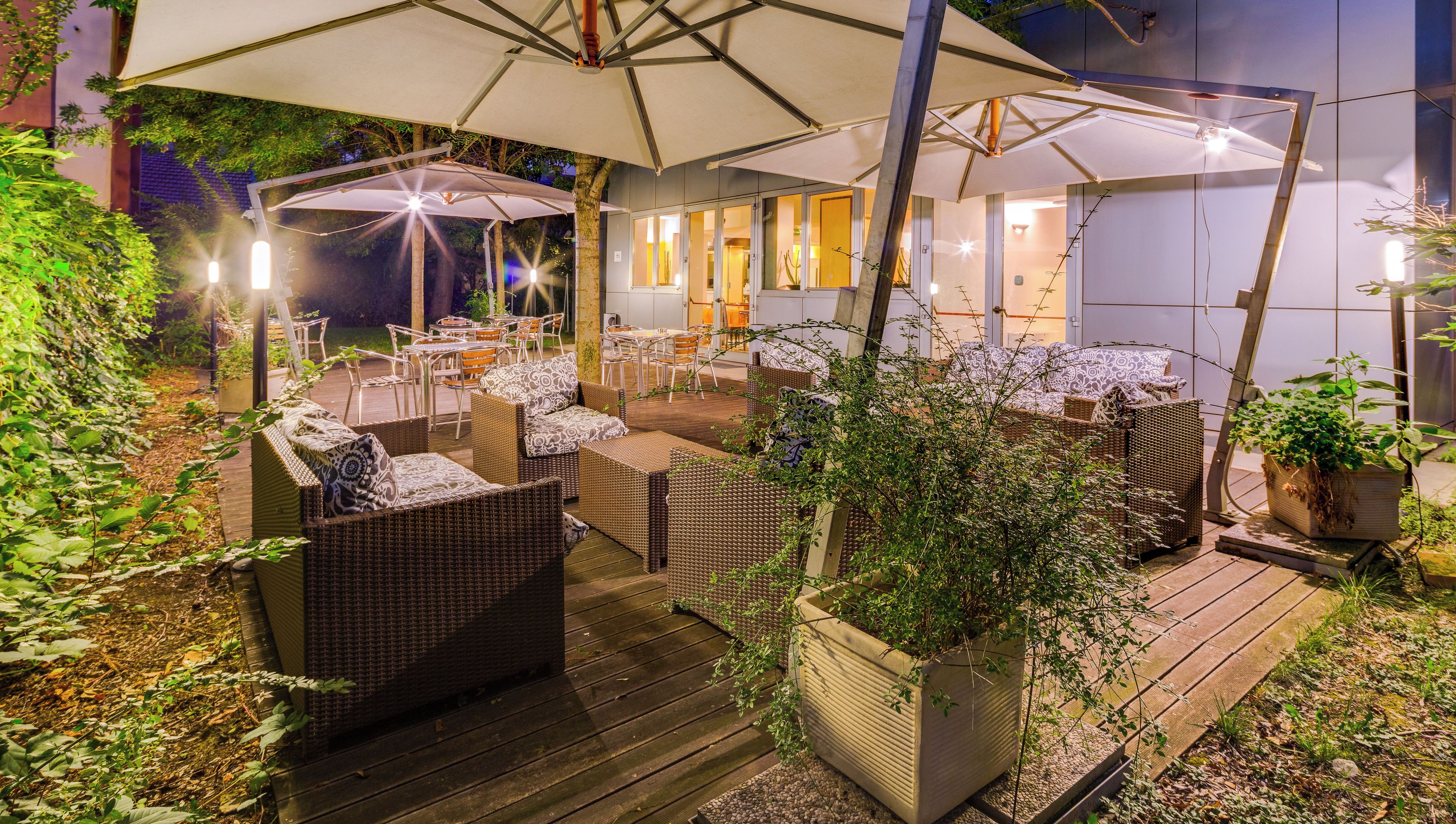 Una terrazza esterna con mobili in vimini, ombrelloni e piante in vaso.