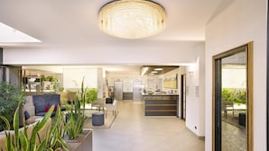 Eine moderne Hotelhalle mit Empfangstresen, Sitzgelegenheiten und einem großen Kronleuchter.