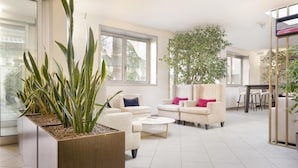 Ein modernes Wohnzimmer mit großem Fenster, zwei Sofas, einem Couchtisch und einem Blumentopf.