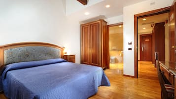 A bedroom with a large bed, wooden wardrobe, and a bathroom visible through an open door.