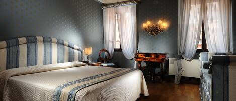 A bedroom with a large bed, a desk, and a chair.