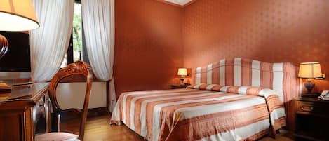 Una habitación de hotel con una cama, mesitas de noche, una silla y cortinas.