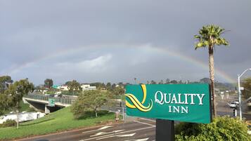 A sign for Quality Inn with a rainbow in the background.