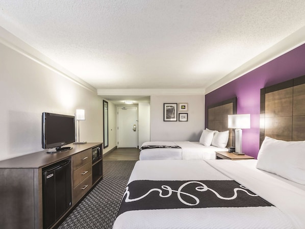 A hotel room with a bed, bedside tables, a TV, a desk, and a wardrobe.